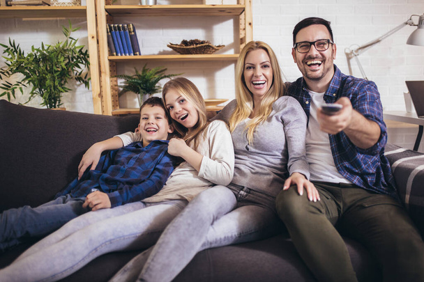 Família feliz assistindo TV juntos em casa e se divertindo juntos. - Foto, Imagem