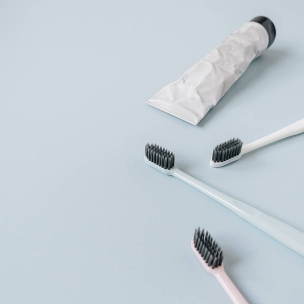Tandenborstels, tandpasta op blauwe achtergrond. Platte lay, bovenaanzicht mondverzorging, tandhygiëne concept. - Foto, afbeelding