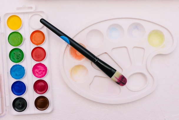 Aquarellfarben, Pinsel und Palette auf weißem Hintergrund. Werkzeuge für Kreativität und Lernen. Artist 's kit. - Foto, Bild