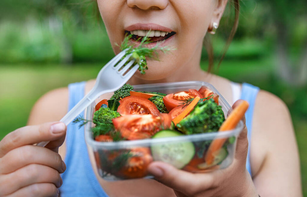 Close-up of a beautiful girl eating fresh vegetable salad, shallow depth of field, selective focus. Healthy food concept - Photo, Image