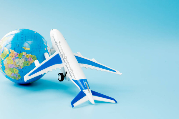Airplane and globe on blue background. Summer or vacation concept. Copy space. - 写真・画像