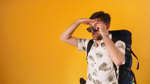 Бородатый 30-летний кавказский мужчина ищет направление с снятыми солнцезащитными очками - Фото, изображение