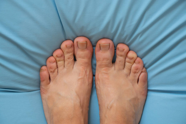 pieds féminins pieds nus sur un matelas bleu, vue de haut en bas - Photo, image