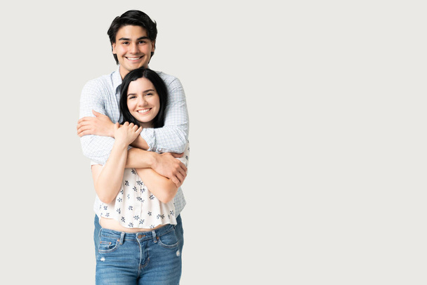 Happy Hispanic young man embracing attractive girlfriend in studio - Foto, immagini