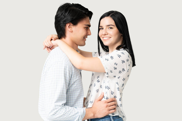 Usmívající se atraktivní mladá žena objímající hispánského muže proti bílému pozadí - Fotografie, Obrázek
