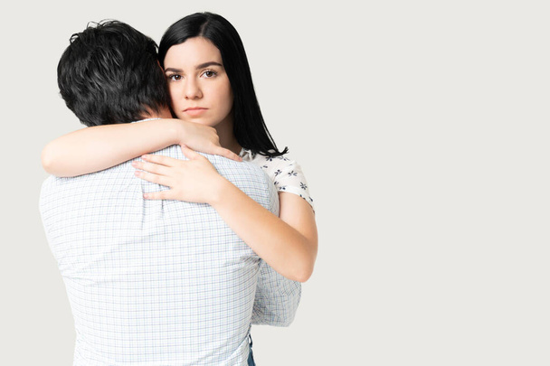 Beautiful young woman looking unhappy while hugging boyfriend - Photo, Image