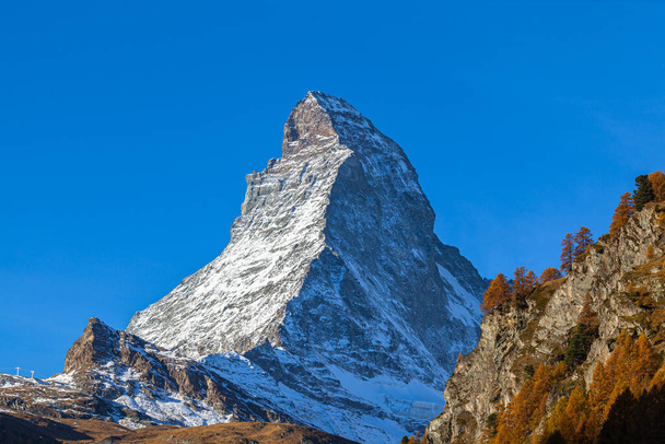 Lenyűgöző kilátás nyílik a híres Matterhorn csúcs a svájci Alpok Zermatt völgyben a napsütéses őszi napon arany fák és fű előtérben, Valais, Svájc - Fotó, kép