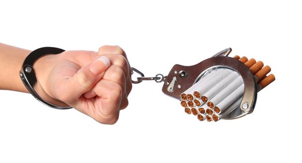 Сигареты и наручники на женской руке изолированы на белом
 - Фото, изображение