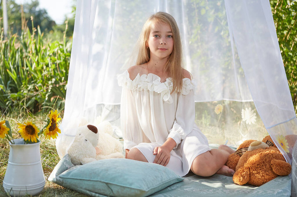 Little girl in white chiffon tent with toy. Childhood, tenderness, beauty - Фото, зображення