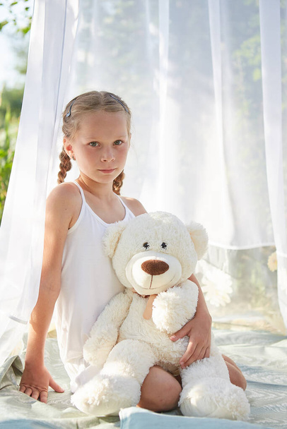 Little girl in white chiffon tent with toy. Childhood, tenderness, beauty - Zdjęcie, obraz