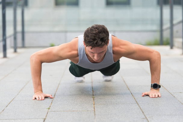 Caucasian athlete man doing push-ups. Fitness man training push up outdoor. young handsome man in sportswear doing push-up. doing exercises for calves and glutes. Handsome fit guy making crunches - 写真・画像