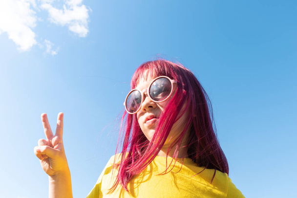 Attractive young girl with pink hair is dancing. Sky background with clouds. Party and fun concept. Kid hair magnificent - Φωτογραφία, εικόνα