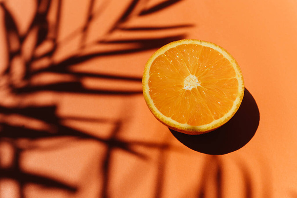 Summer tropical composition. Shadow of palm leaves and tropical fruits on orange background. - Foto, Bild