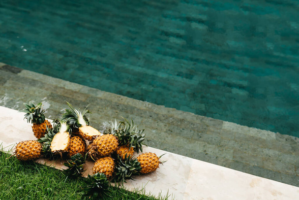 Healthy Raw Organic Food. Fresh Ripe Pineapples near Pure Water In Swimming Pool. - Фото, изображение