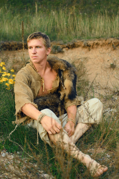 giovane contadino cacciatore medievale siede su una collina di sabbia - Foto, immagini