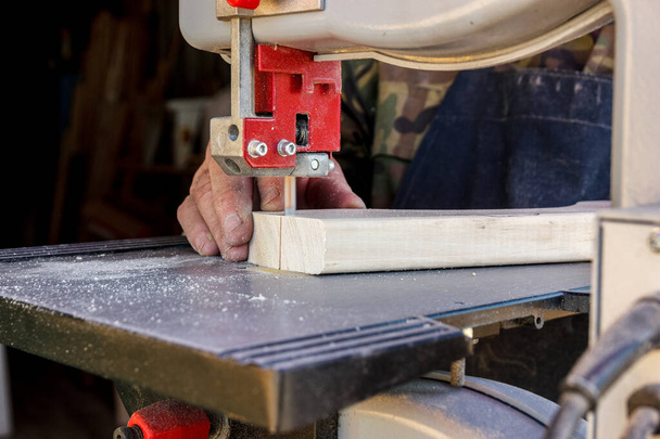 Close-up arbeidershanden in de timmerwerkplaats snijden het logboek in planken met behulp van bandzaag. Ruw hout en houtwerk - Foto, afbeelding