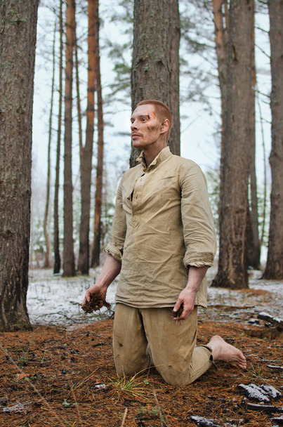 2. Dünya Savaşı üniformalı genç adam ve yalınayak kış ormanında diz çöker. - Fotoğraf, Görsel
