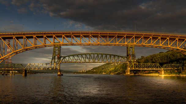Ηλιοβασίλεμα πάνω από τη δεύτερη γέφυρα Narrows (Ironworkers Bridge) της Trans Canada Highway και μια σιδηροδρομική γέφυρα, πάνω από Burrard Inlet και το λιμάνι του Βανκούβερ - Φωτογραφία, εικόνα