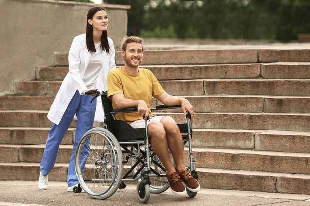 屋外の車椅子の医者と若者 - 写真・画像