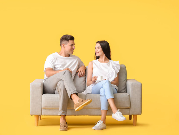 Young couple relaxing on sofa against color background - Fotó, kép