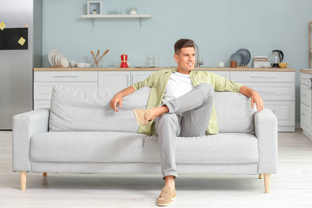 Młody mężczyzna relaksuje się na kanapie w domu - Zdjęcie, obraz