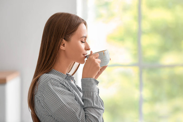 Beautiful young woman drinking tea at home - Фото, зображення