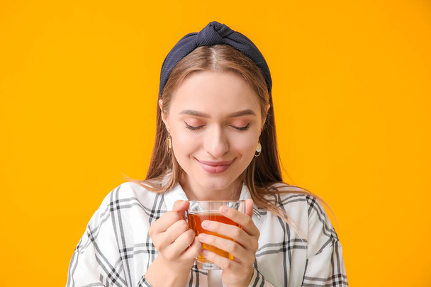 Belle jeune femme avec tasse de thé sur fond de couleur - Photo, image