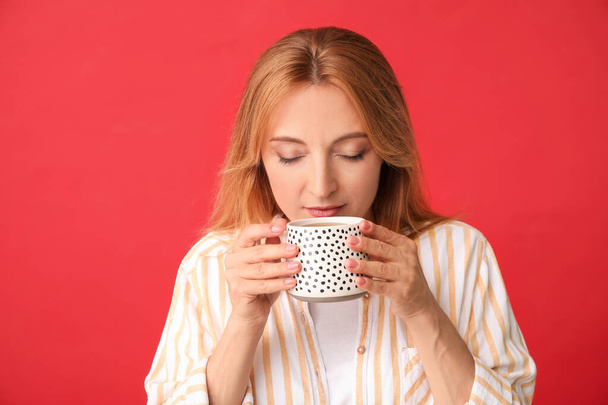 Belle femme avec tasse de thé sur fond de couleur - Photo, image