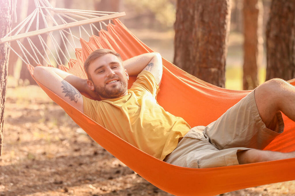 Jeune homme relaxant en hamac à l'extérieur - Photo, image