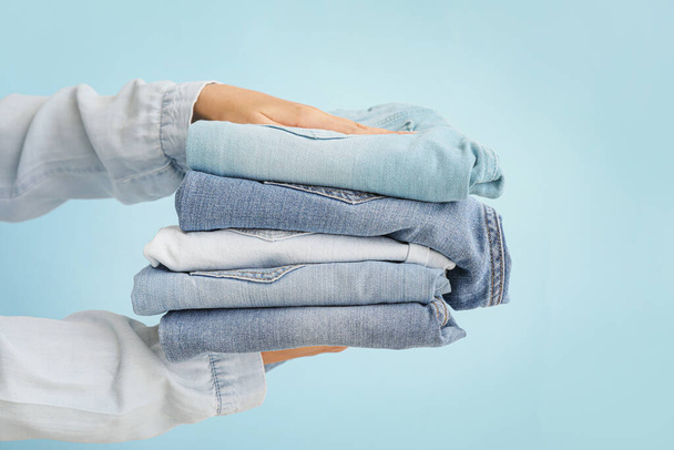 Female hands with stylish jeans pants on color background - Foto, immagini