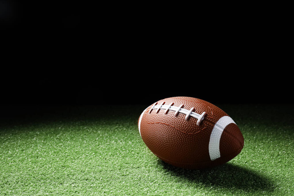 Rugby palla su erba verde contro sfondo scuro - Foto, immagini