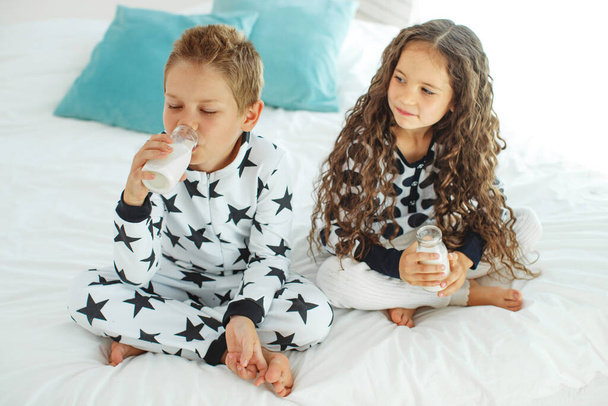 Τα παιδιά πίνουν γάλα. Αγόρι και κορίτσι στο σπίτι.  - Φωτογραφία, εικόνα