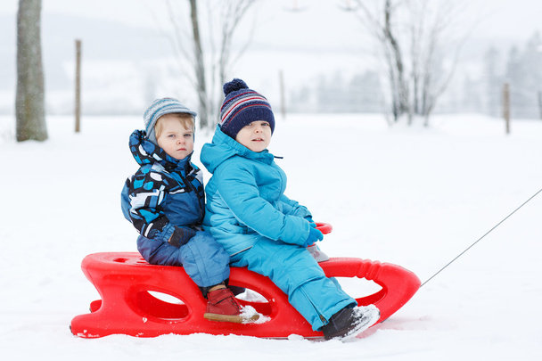 Deux petits frères et sœurs s'amusent sur luge le jour de neige d'hiver
 - Photo, image
