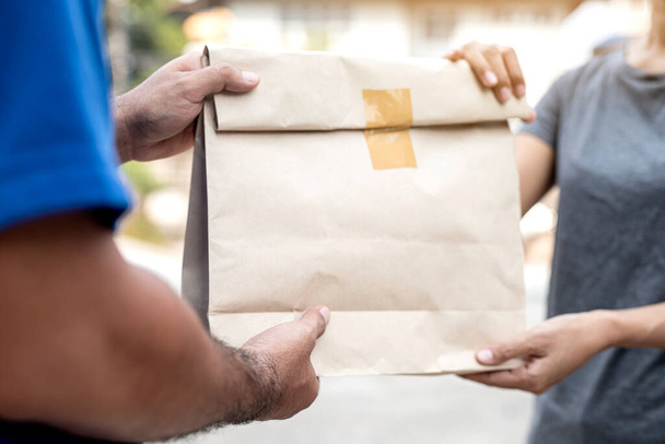 Kadın eli, teslimatçı, teslimat konsepti olan teslimatçıdan paket yiyecek teslimatını kabul ediyor.. - Fotoğraf, Görsel