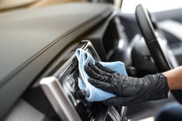 Esta imagen es una imagen de limpiar el coche por un paño de microfibra azul con guantes que usan la mano.Concepto de lavado de coches. - Foto, imagen