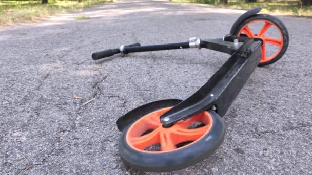 De scooter ligt op het asfalt nadat er een ruiter afvalt. Het achterwiel draait, wat symboliseert dat de val recent gebeurde. Slordig rij- en haastconcept - Video