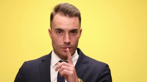 sexy elegante zakenman in pak houden vinger naar mond en het maken van stilte gebaar op gele achtergrond - Video