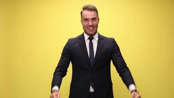 homem de negócios elegante alegre em terno segurando punhos no ar, rindo, olhando para cima e celebrando a vitória no fundo amarelo
 - Filmagem, Vídeo