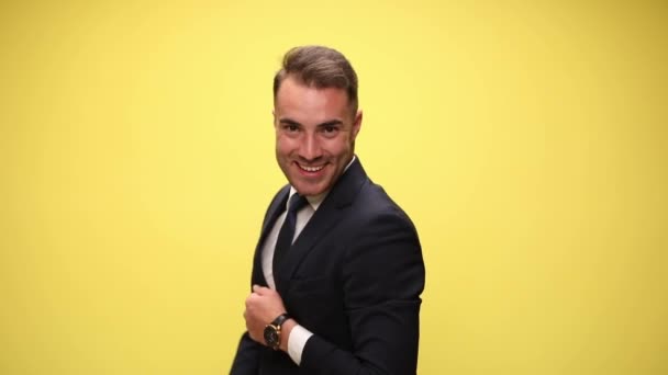 happy elegant businessman smiling, pointing fingers, waving, doing piruettes with hands, twirling hands around, taking a bow, moving hands gesturing, dancing laughing on yellow background - Footage, Video