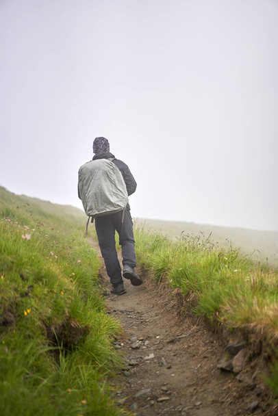 Túrázó esőkabátos és nagy hátizsák túrázás a hegyekbe - Fotó, kép