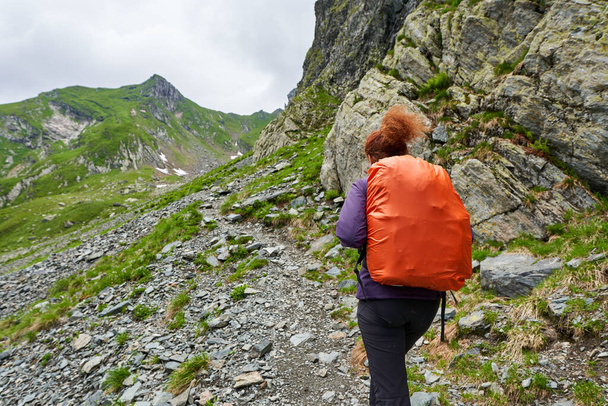 Female tourist with backpack hiking on a trail in the mountains - Foto, imagen