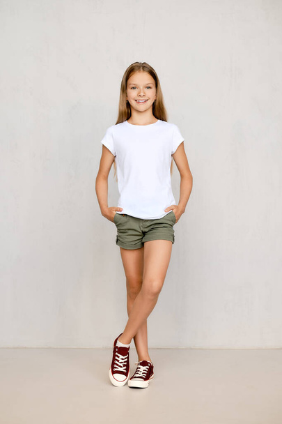 Full length portrait of positive teenager girl standing straight with both hands in pockets - Fotoğraf, Görsel