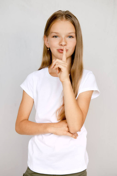 Portrait of teenager girl holding finger near lips and showint keep silence sign - Photo, Image