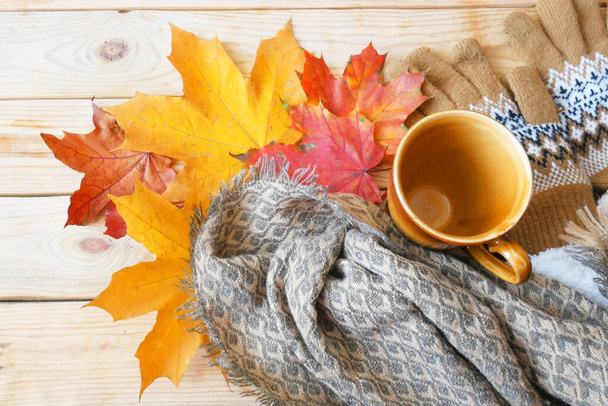 Herbstliches Laub, heiße dampfende Tasse Morgenkaffee und ein warmer Schal auf hölzernem Hintergrund, herbstliches Stimmungskonzept - Foto, Bild
