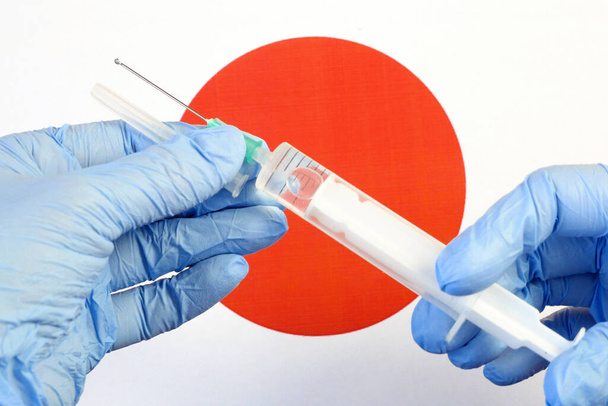 Aşılı şırınga, Japon bayrağının arka planında bir eldivende, Coronavirus 'a karşı aşı, Warp Hızı Operasyonu - Fotoğraf, Görsel