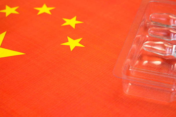 ruiskua rokotteella pidetään käsin käsineessä Kiinan lipun taustalla, rokote koronavirusta vastaan, operaatio Poimunopeus - Valokuva, kuva