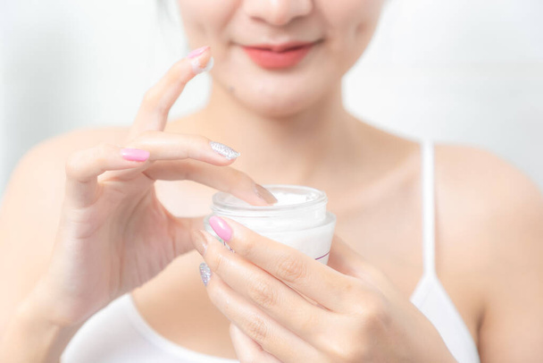 Une femme tient une crème hydratante dans sa main et sa peau et les rides des impuretés. - Photo, image