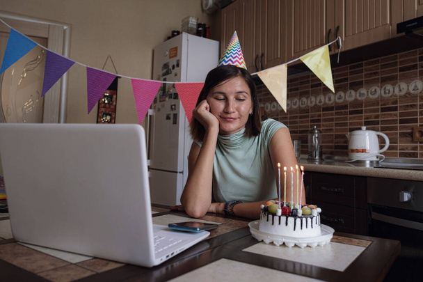 Chica celebrando cumpleaños en línea en tiempo de cuarentena. Mujer celebrando su cumpleaños a través de videollamada fiesta virtual con amigos. Auténtico hogar decorado lugar de trabajo. Brote de Coronavirus 2020. - Foto, imagen