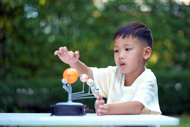 Azjatycki chłopiec Żywego Układu Słonecznego Zabawki, Home Learning Equipment, podczas nowych normalnych zmian po koronawirusie lub po wybuchu pandemii zakrzepowej-19 - Zdjęcie, obraz