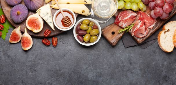 Antipasto plate with prosciutto, cheese, figs and grapes. Appetizer board and white wine. Top view flat lay with copy space - Photo, Image